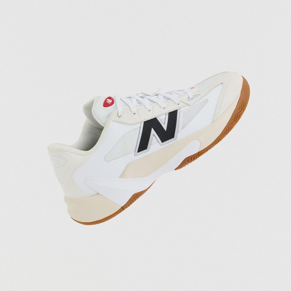 A white athletic shoe with beige accents, a gum outsole, and a large black &ldquo;N&rdquo; logo is shown against a plain white background.