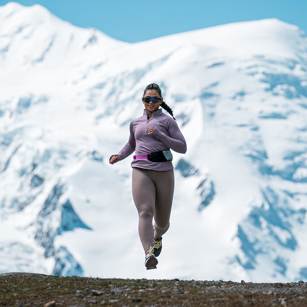 Person running outdoors with snowy mountains in the background.