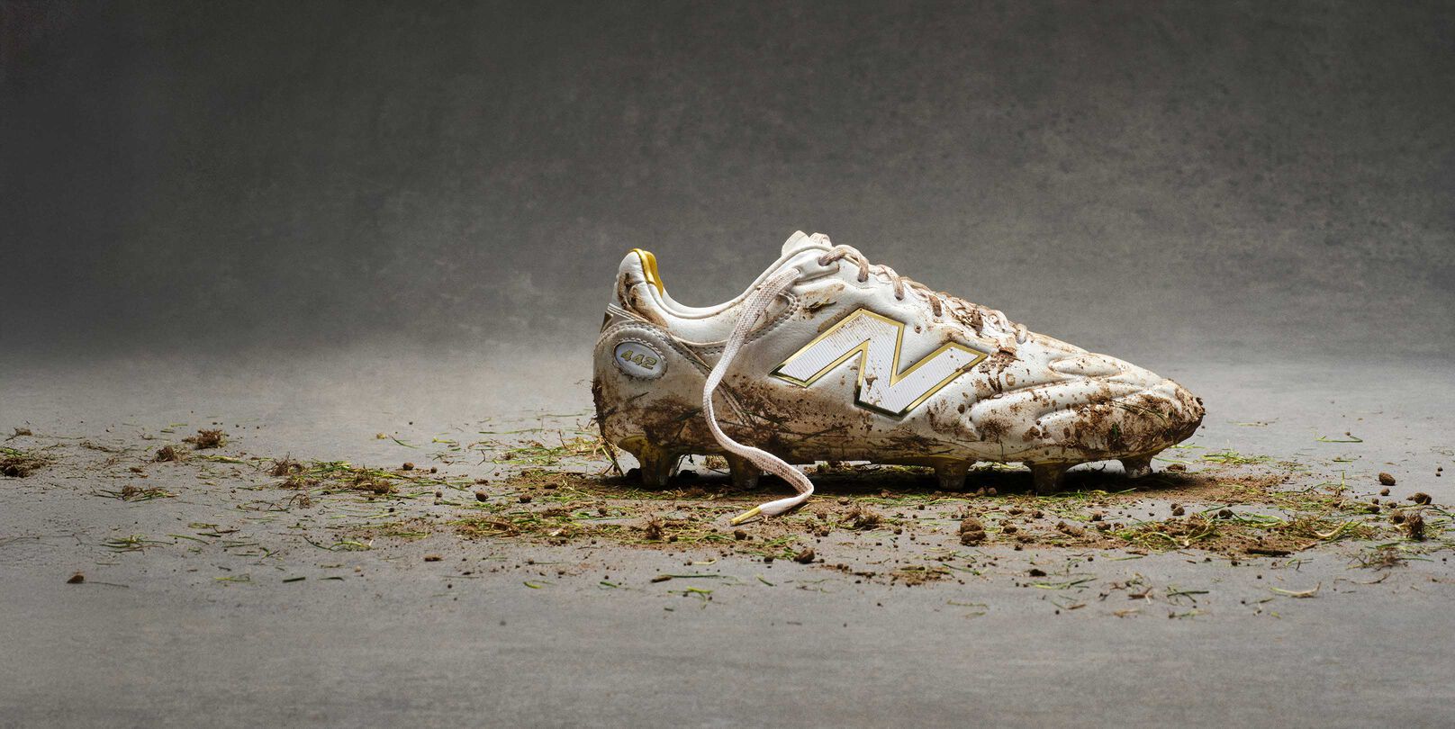 White and gold cleats covered in dirt and grass