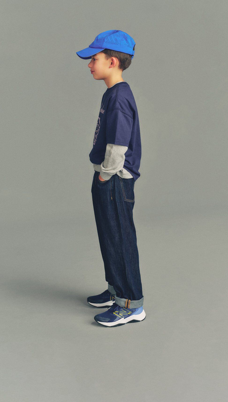 Kid wearing Rave Run shoes standing against a grey studio background.