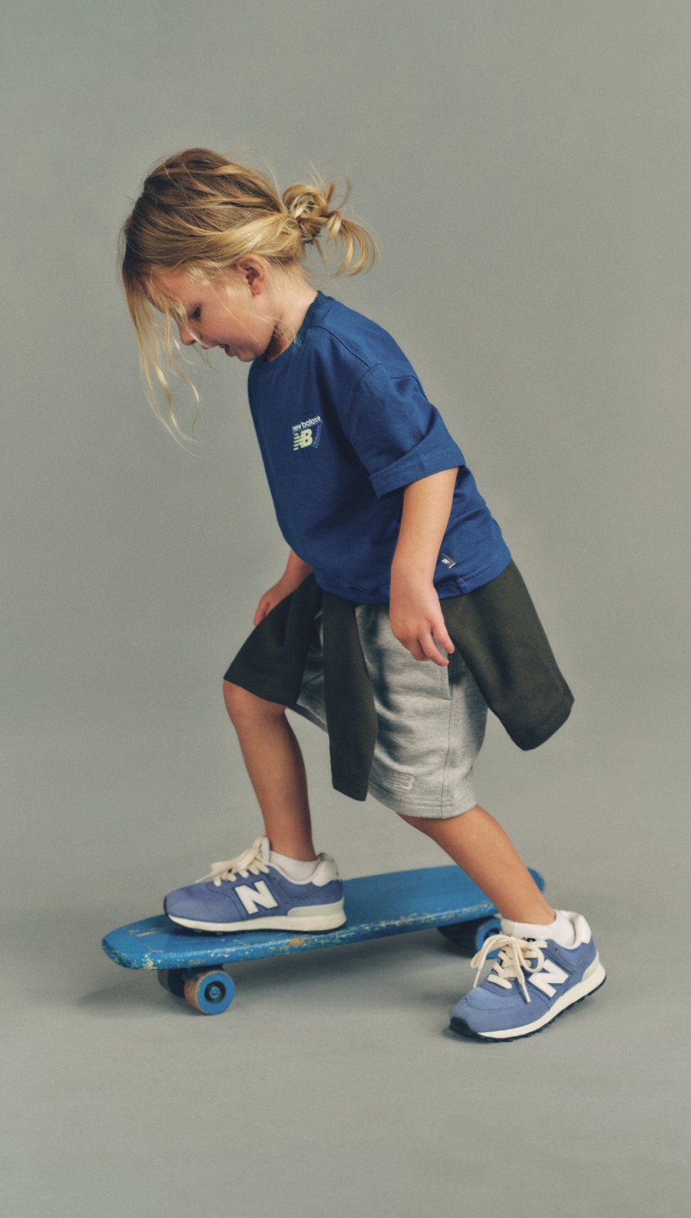 Young girl in a navy tshirt riding a skateboard.