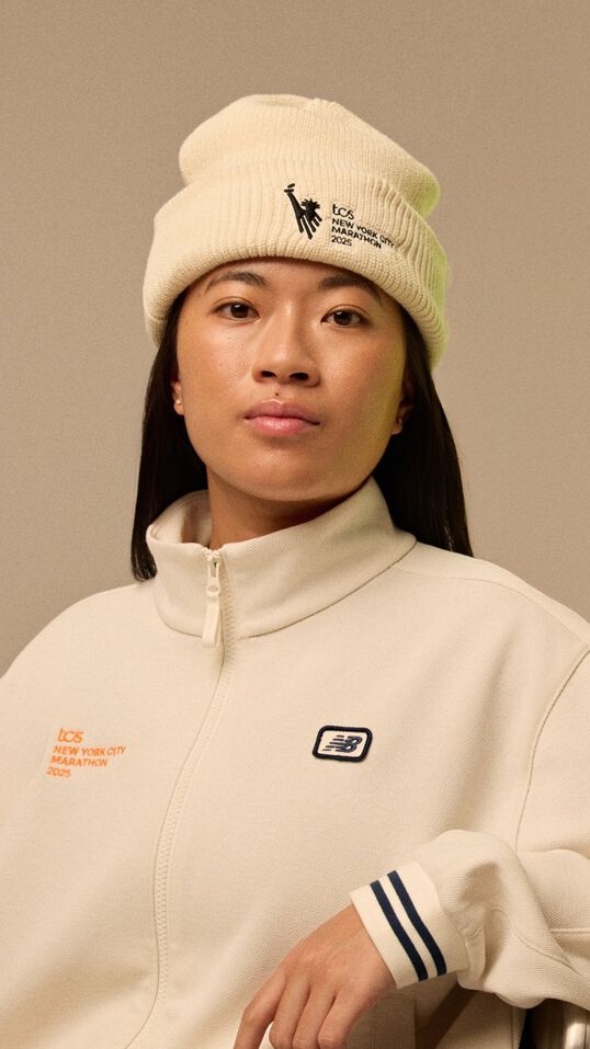 A woman wearing light beige clothes in front of a beige background. 