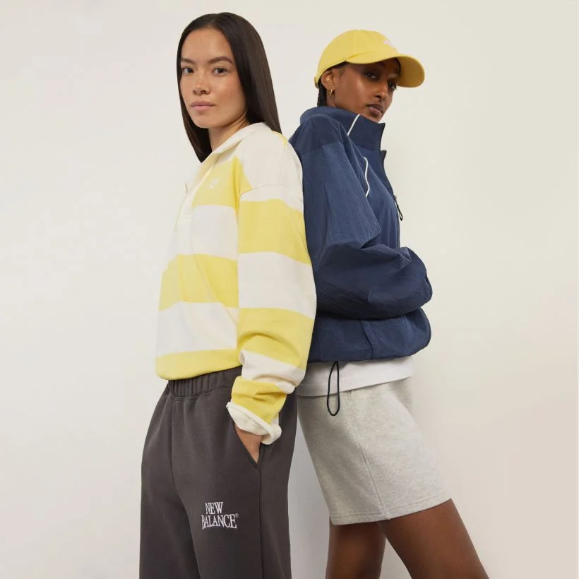 Two women standing back to back and looking at the viewer.