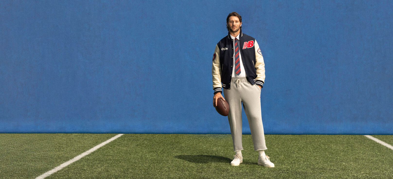Young athlete standing on a field with a blue background wearing a custom jacket.