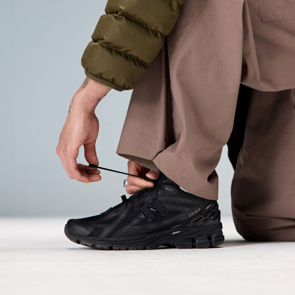 Closeup of an individual kneeling down to tie the laces on the 1906R 