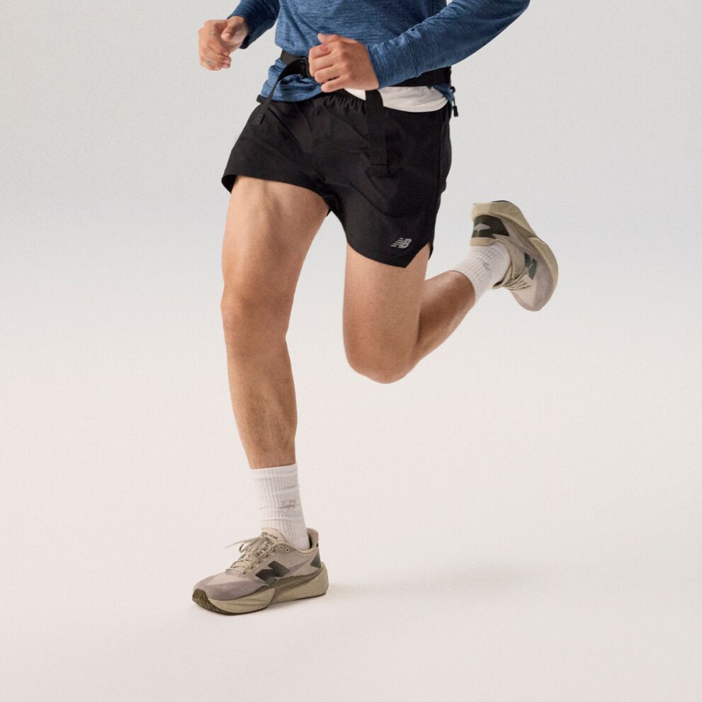 Joven corriendo con una chaqueta azul marino sobre un fondo gris.