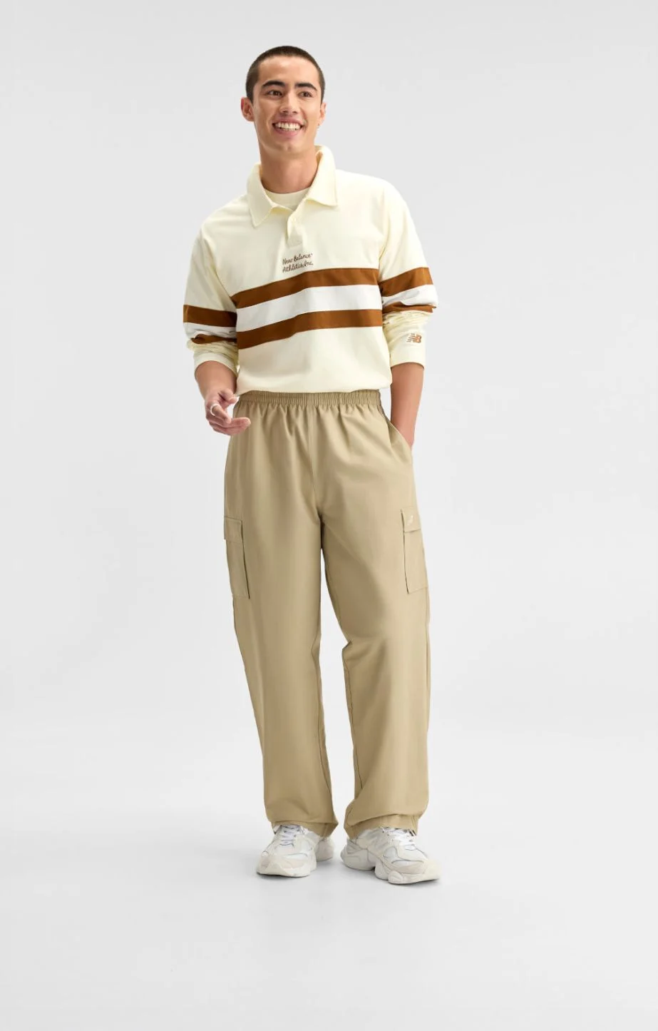  A man wearing cream and brown New Balance gear on a white background. 