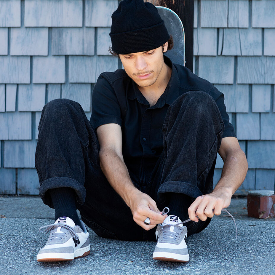El skater Ronnie Kessner sentado en su patineta usando ropa New Balance y calzado Numeric