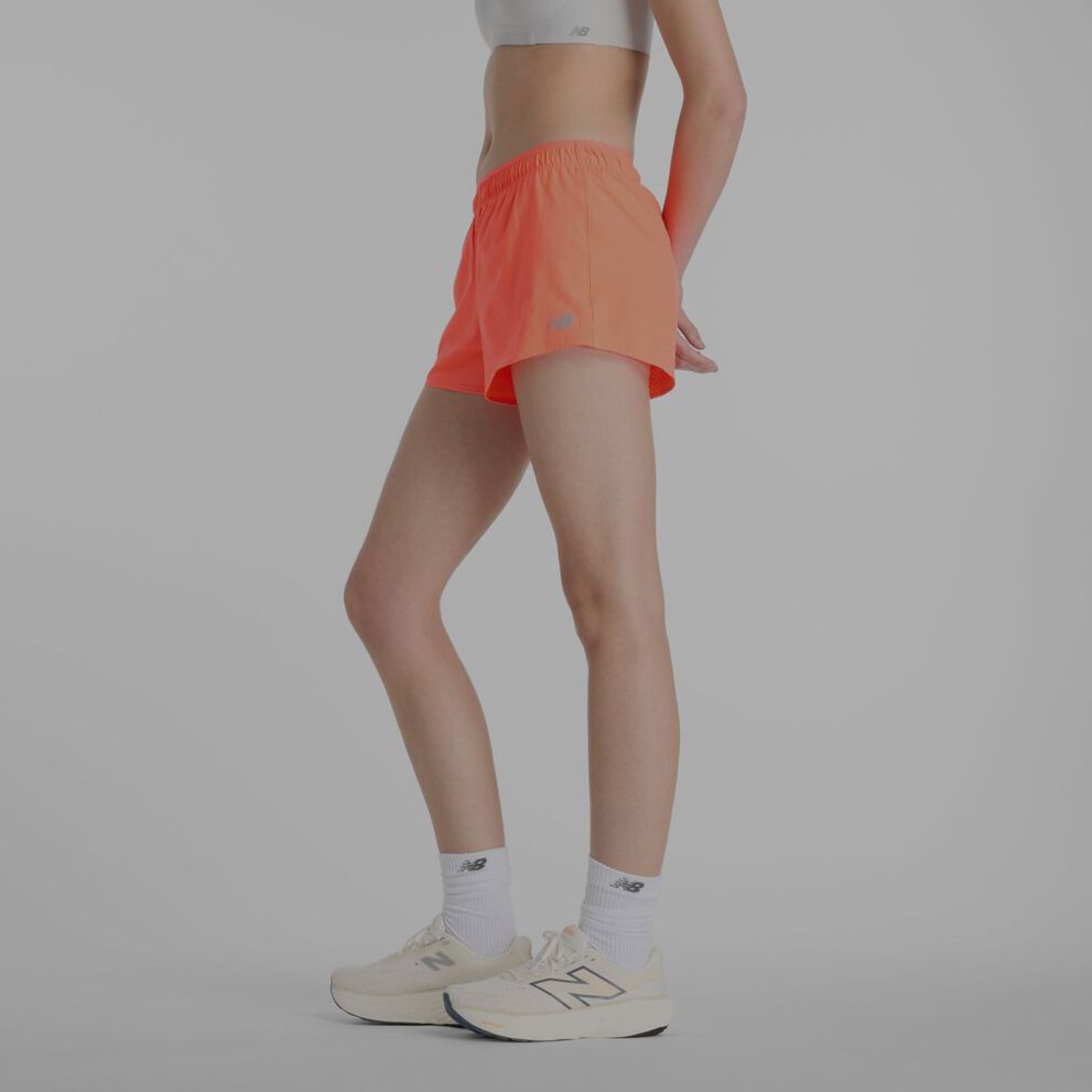 A woman wearing orange New Balance shorts.