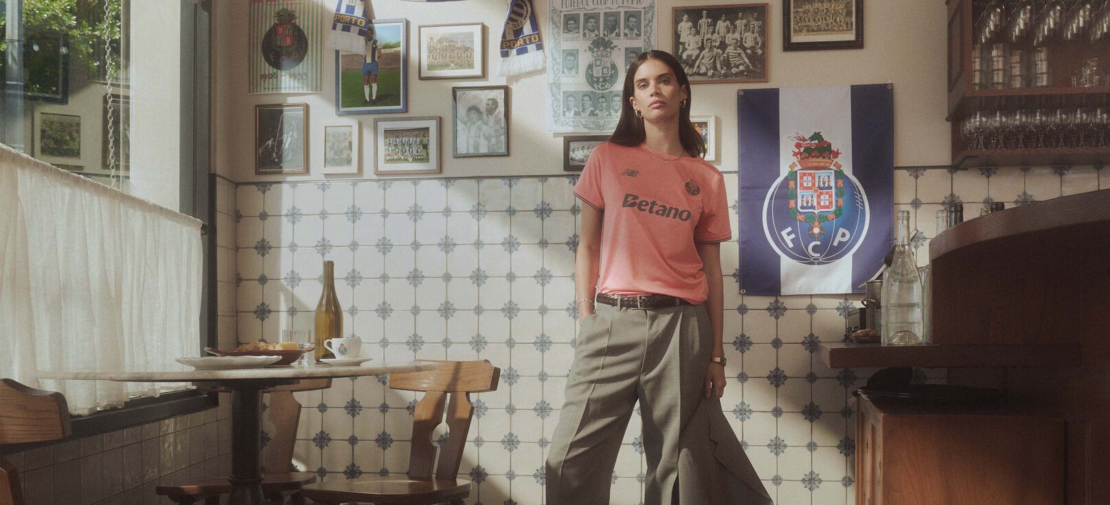 Sara Sampaio standing in a cafe environment wearing the FC Porto Away kit. 