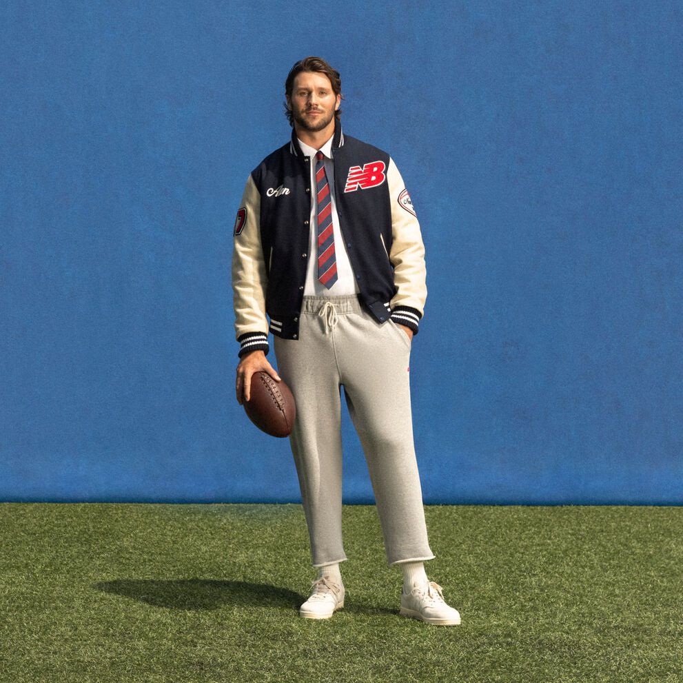 Young athlete standing on a field with a blue background wearing a custom jacket.