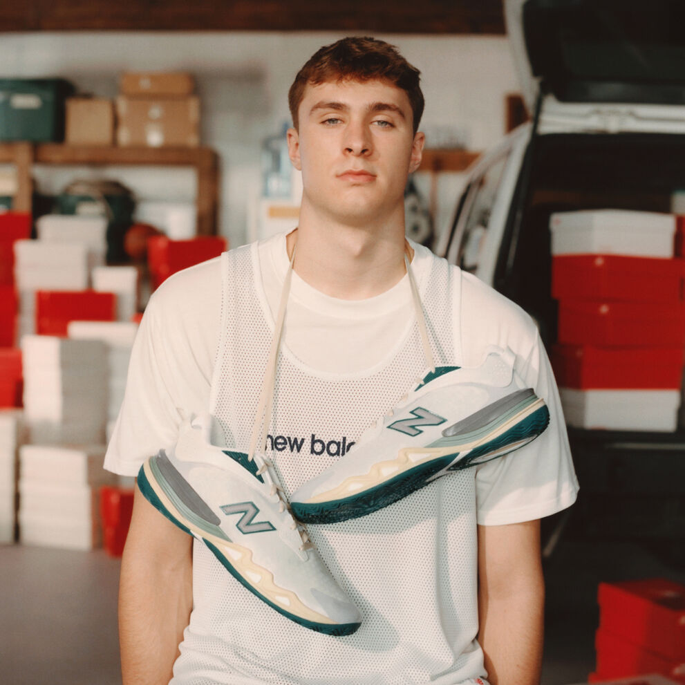 Young athlete standing in front of a garage with shoes hanging around his neck.