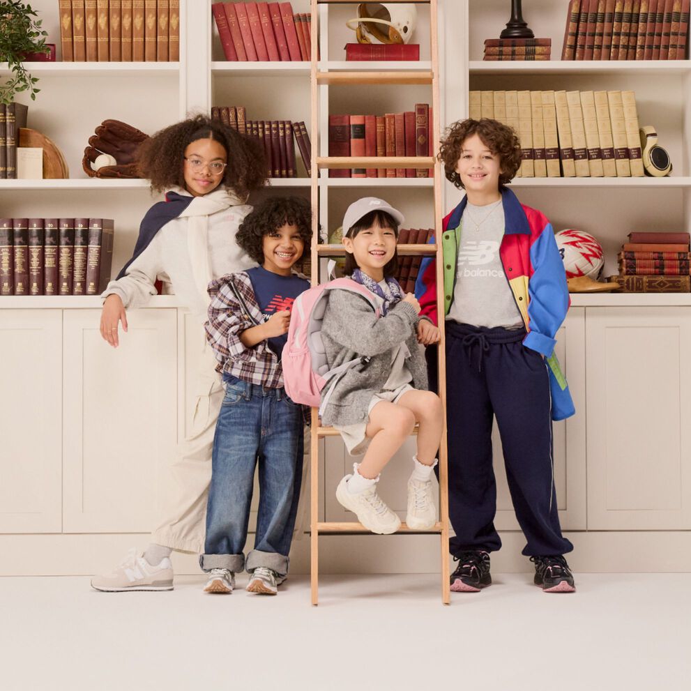 Group of young kids standing in front of a bookshelf. 