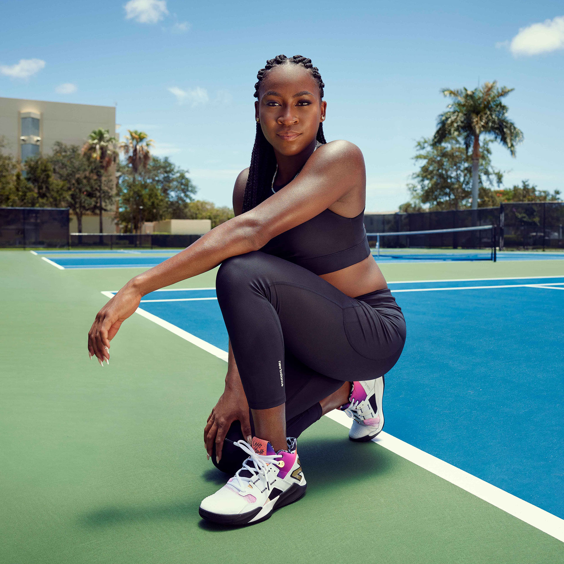 Coco posing on one knee on the tennis court.