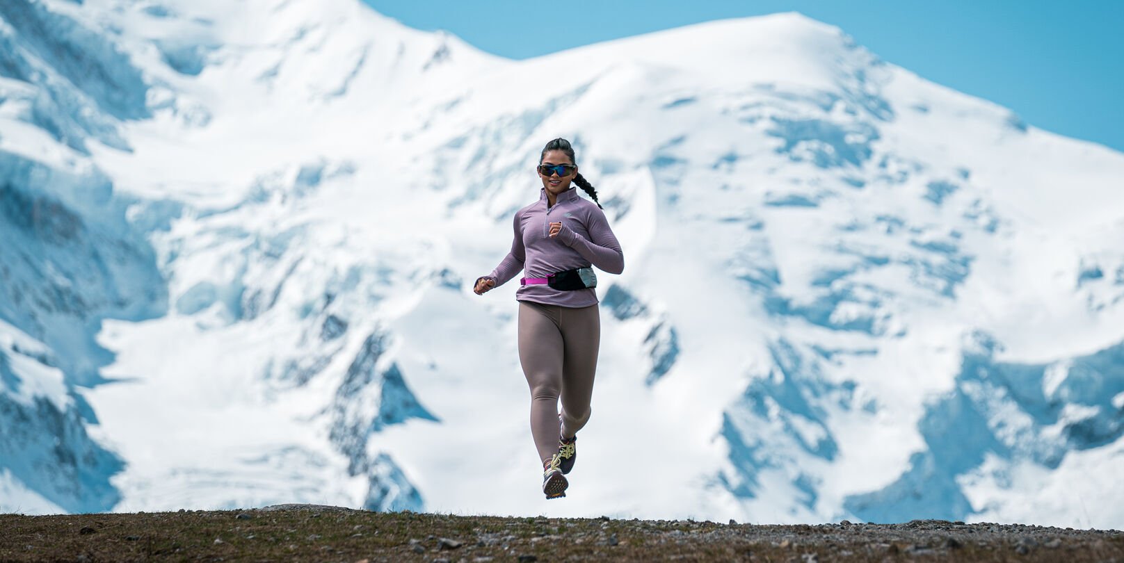Person running outdoors with snowy mountains in the background.