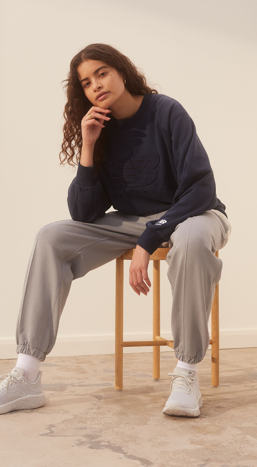 Young woman sitting in a room with earth tone colors on his outfit.