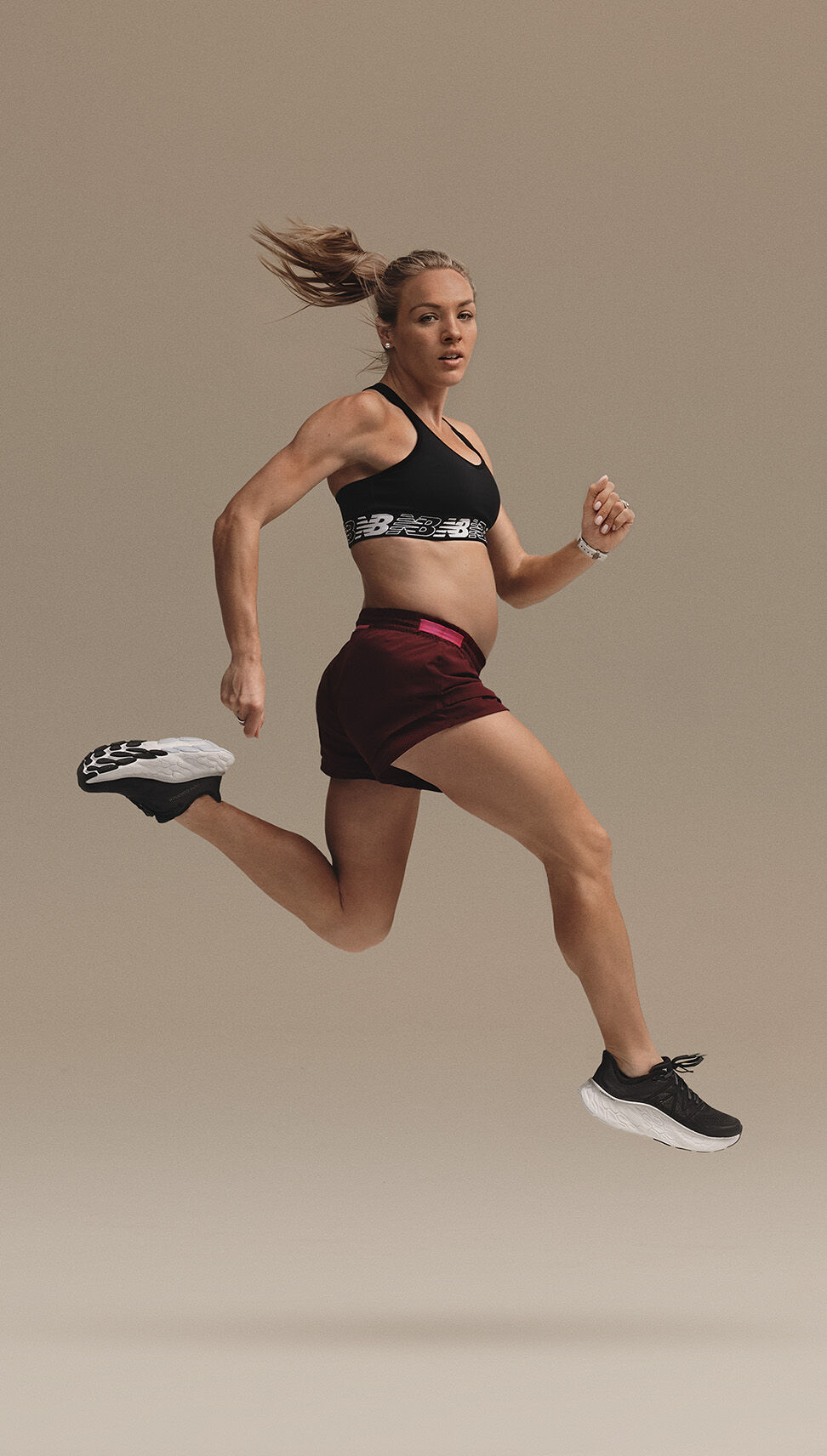 Pregnant woman in a mid-air running pose wearing NB running gear 
