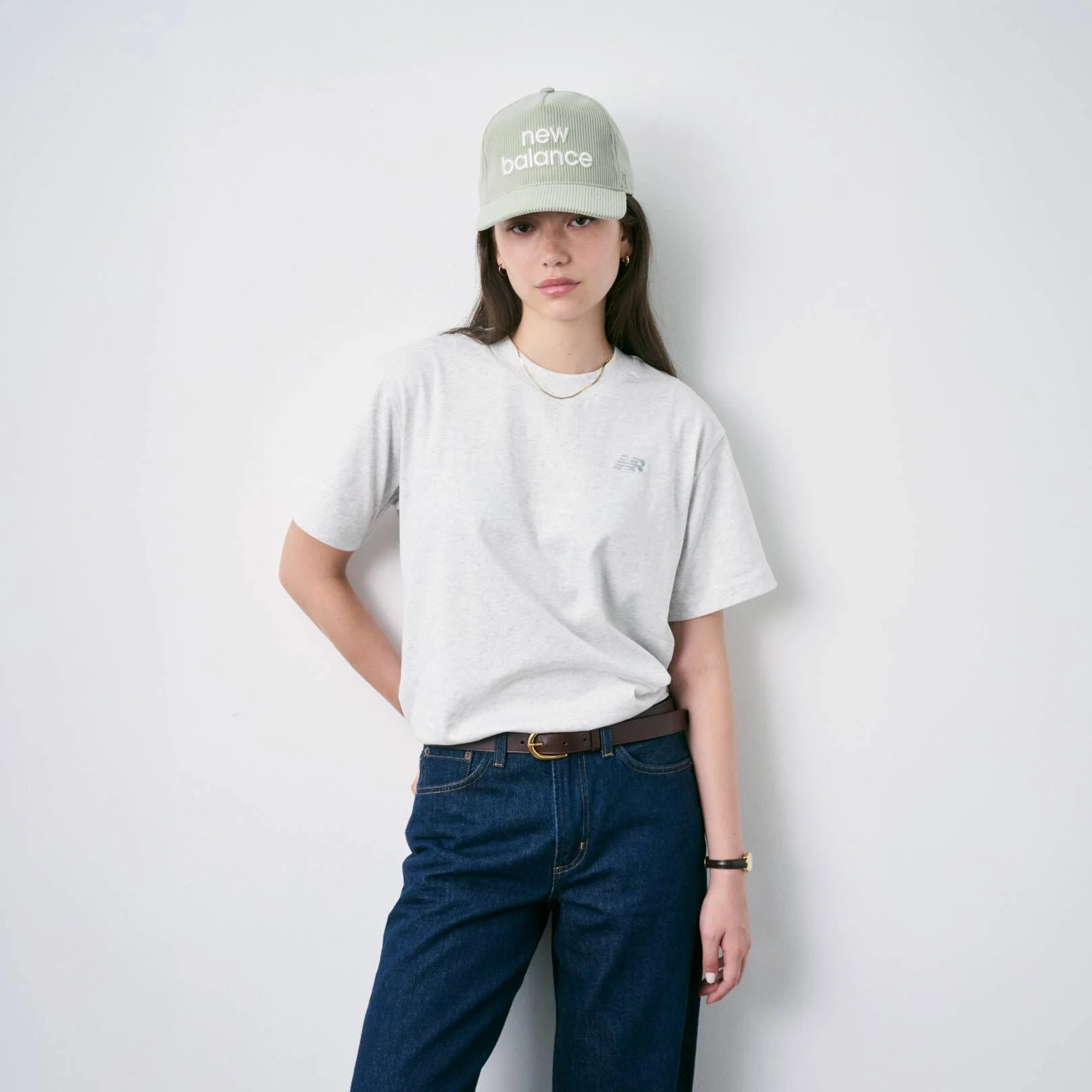 Woman sitting on the floor wearing New Balance shoes and hat
