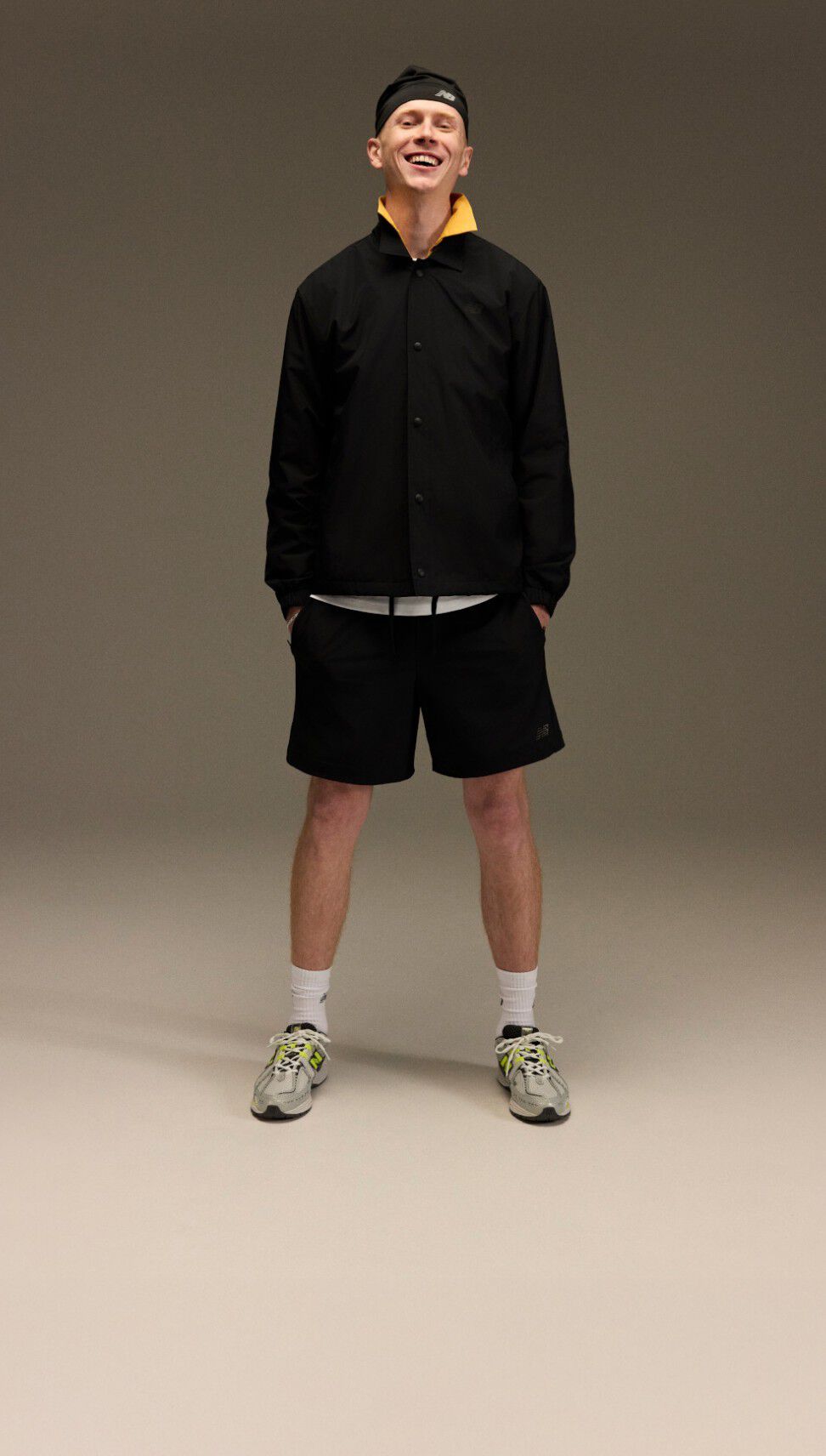 A male standing with an athletic outfit in front of a brown and tan background.