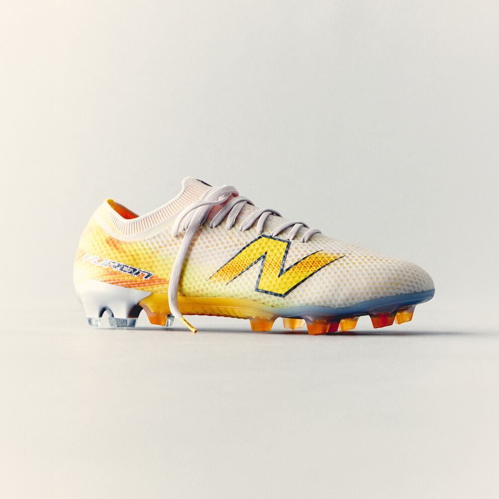 White and yellow New Balance soccer cleat with a lightweight mesh upper and molded studs displayed against a clean white background.