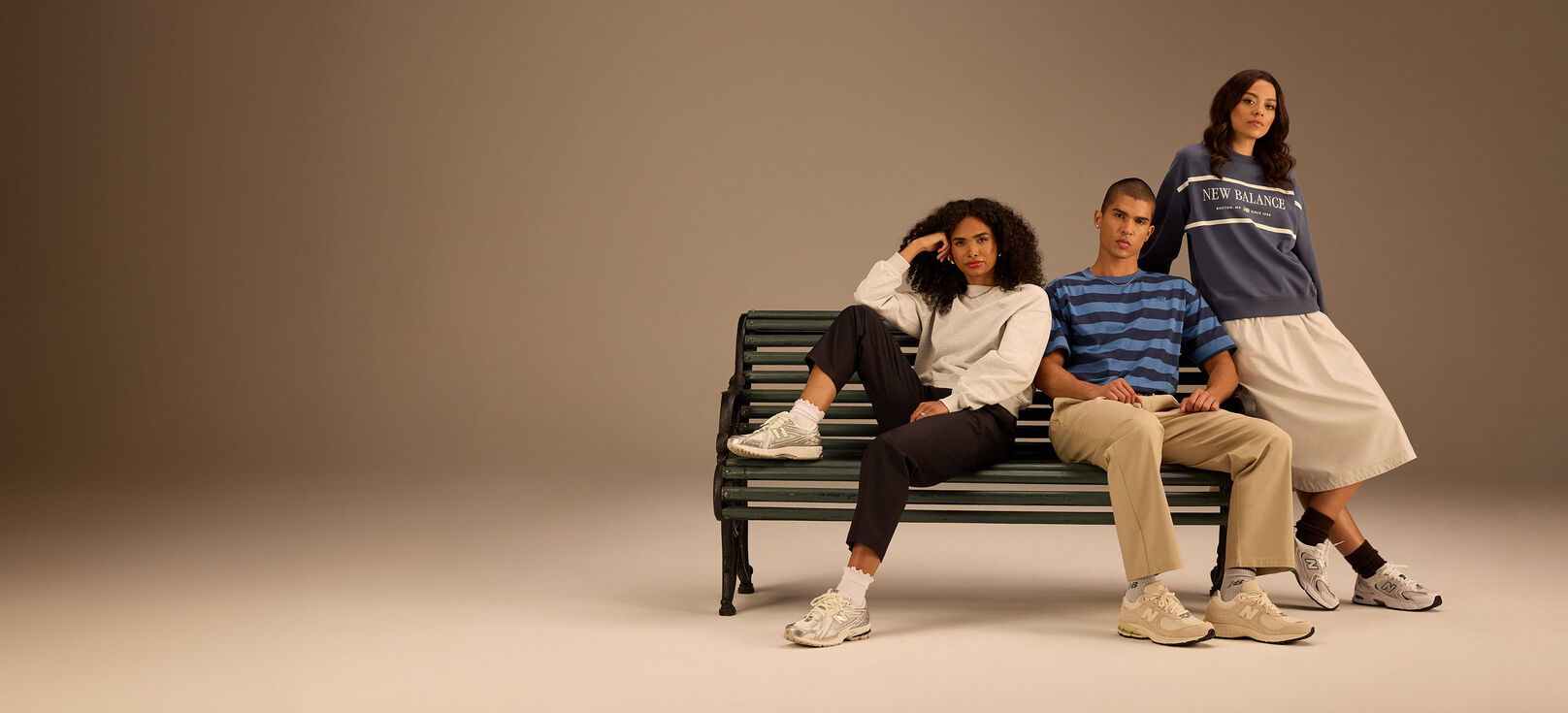 Group of men and women wearing New Balance running clothing and shoes posed against beige background in studio environment