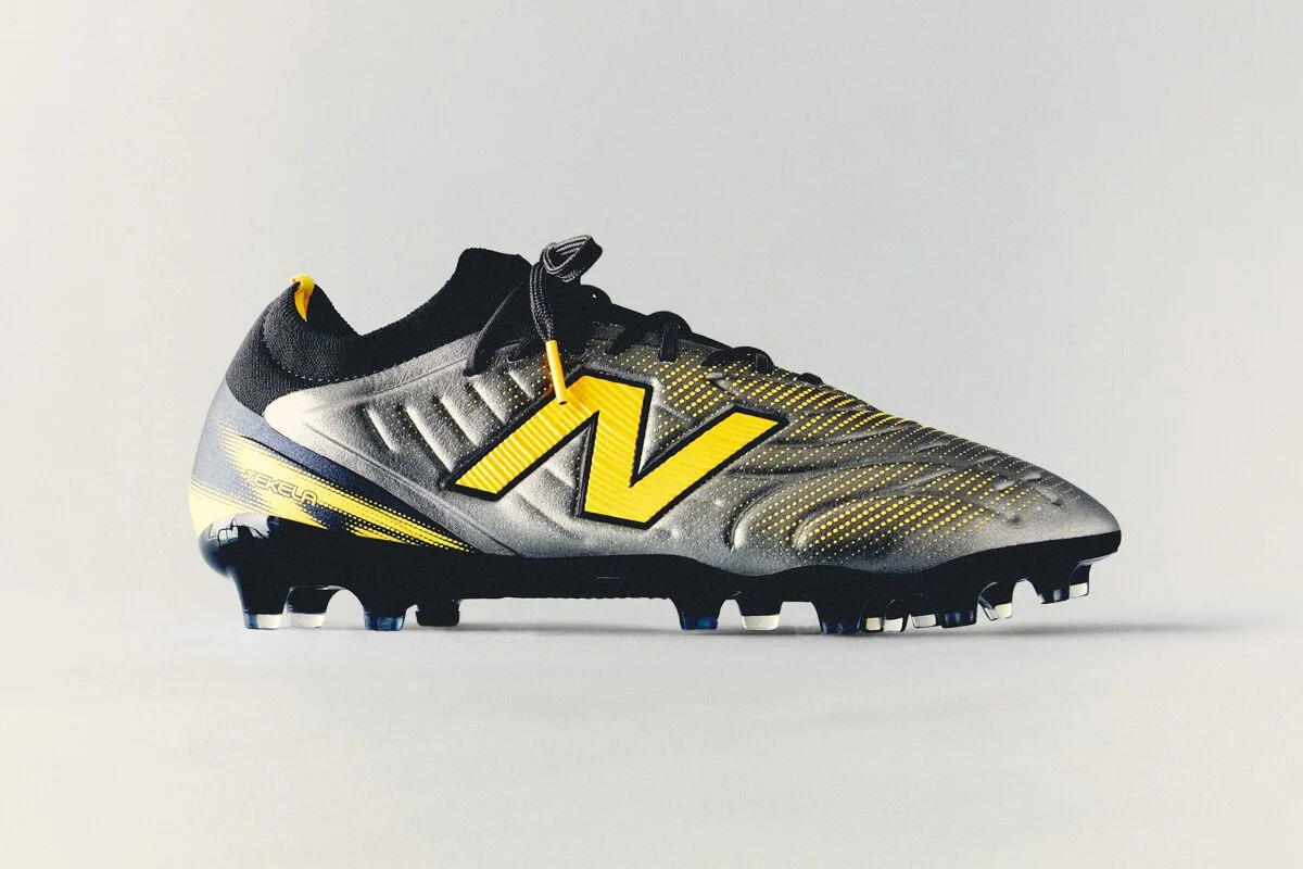 Black and yellow New Balance soccer cleat with textured detailing and molded studs displayed against a clean white background.