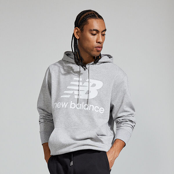Waist-up image of a young man wearing a heather grey NB Essentials hoodie and black sweatpants 