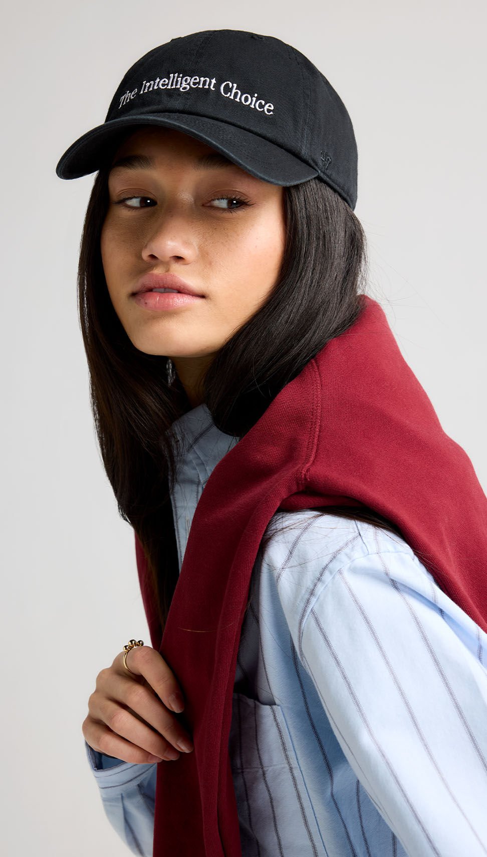 A close-up portrait shot of a woman wearing a black &lsquo;47 hat with the text &ldquo;The intelligent choice&rdquo; front and center of the hat. 
