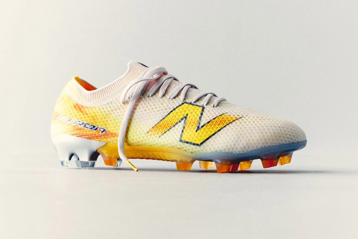White and yellow New Balance soccer cleat with a lightweight mesh upper and molded studs displayed against a clean white background.