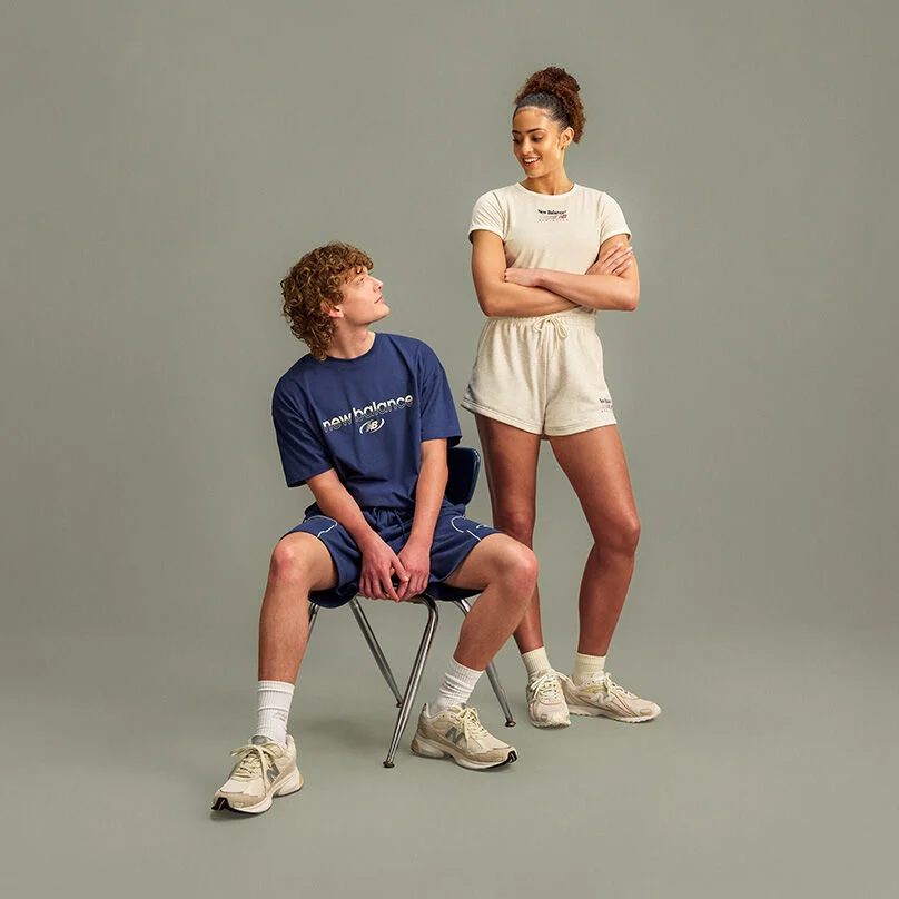 Two people are positioned against a plain light gray studio background with a clean, minimal setup and ample empty space below them.