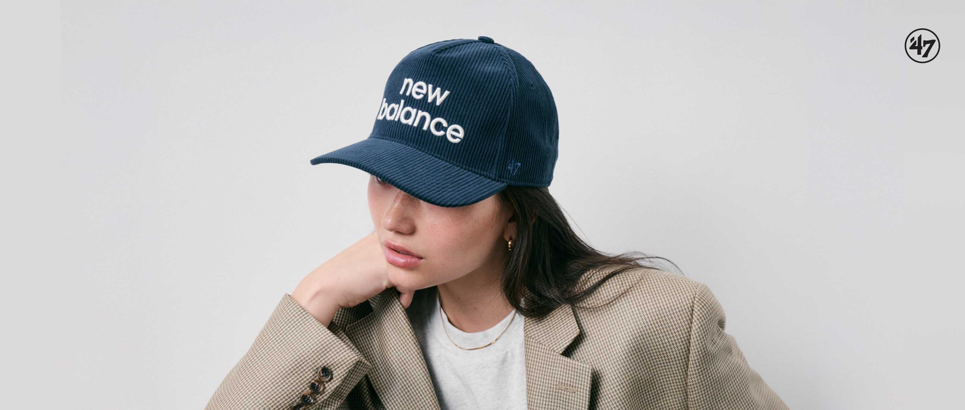 Mujer con gorra New Balance de pie frente a una pared blanca