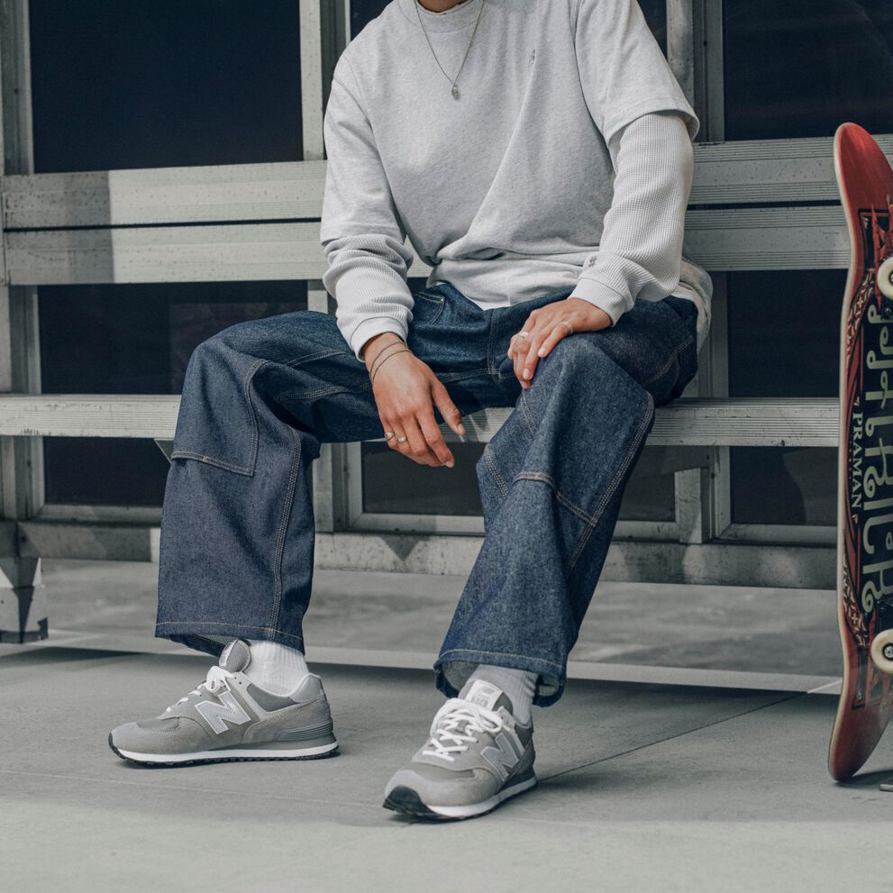 Knee down image of a person wearing a pair of grey 574