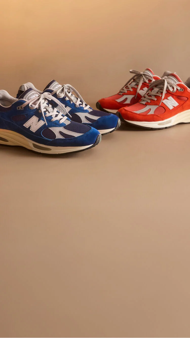 Dos pares de zapatillas New Balance Made in UK en un estudio de color beige.&nbsp;