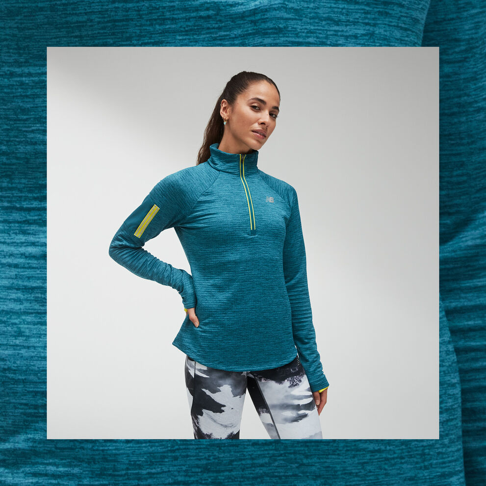 A woman posing in a teal NB Heat Grid Half Zip with neon yellow accents