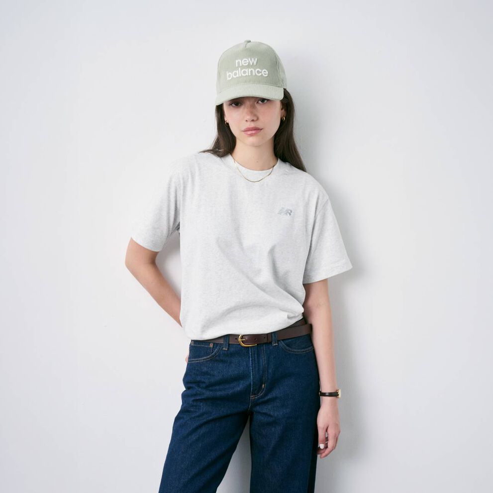 Woman sitting on the floor wearing New Balance shoes and hat