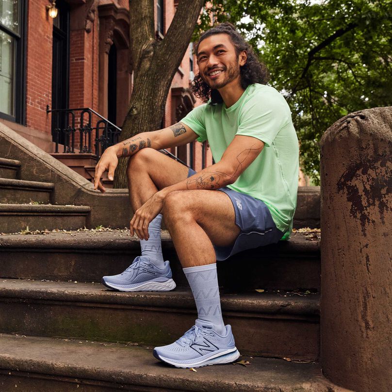 Person wearing 860v13 shoes sitting on the steps of a brownstone apartment.