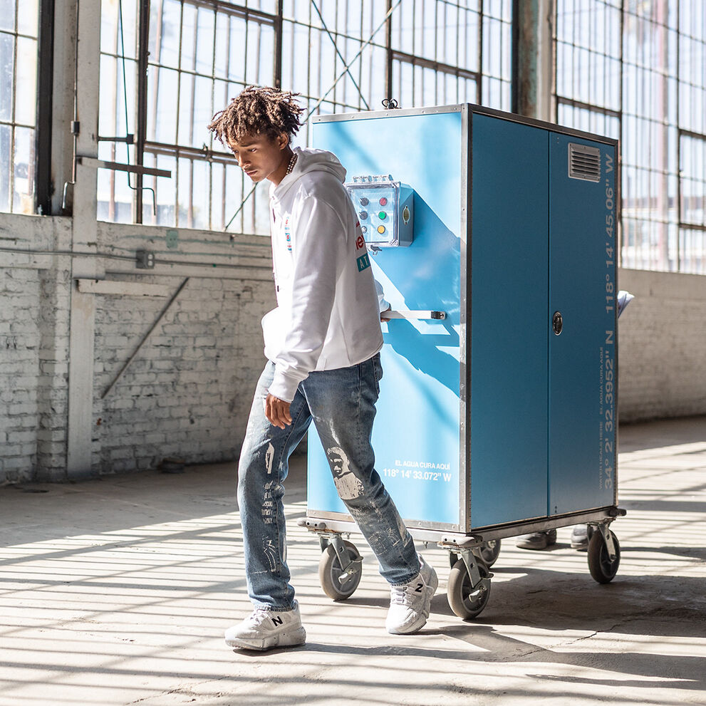 Jaden Smith walking through an industrial building wearing a white NB Essentials hoodie with jeans and his signature NB Vision Racer sneakers 
