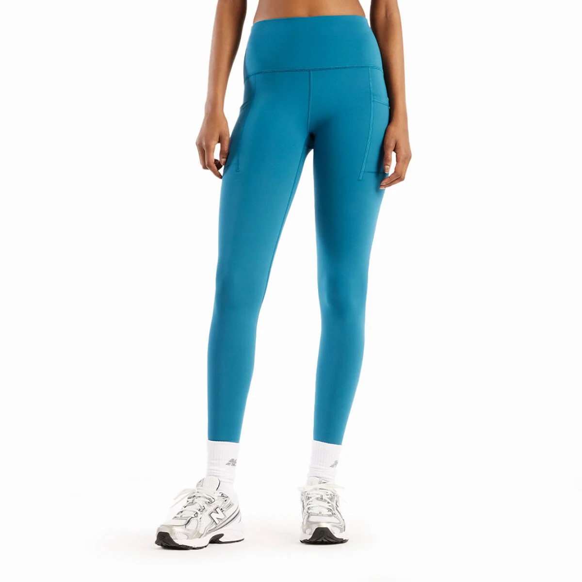 Primer plano de unas mallas de correr azules con un cintur&oacute;n utilitario combinadas con zapatillas de correr verde brillante sobre fondo blanco.