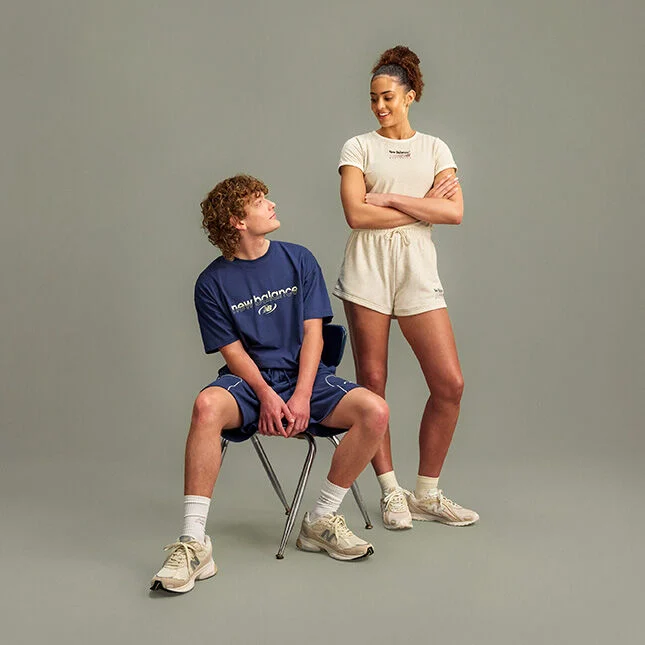 Two people are positioned against a plain light gray studio background with a clean, minimal setup and ample empty space below them.