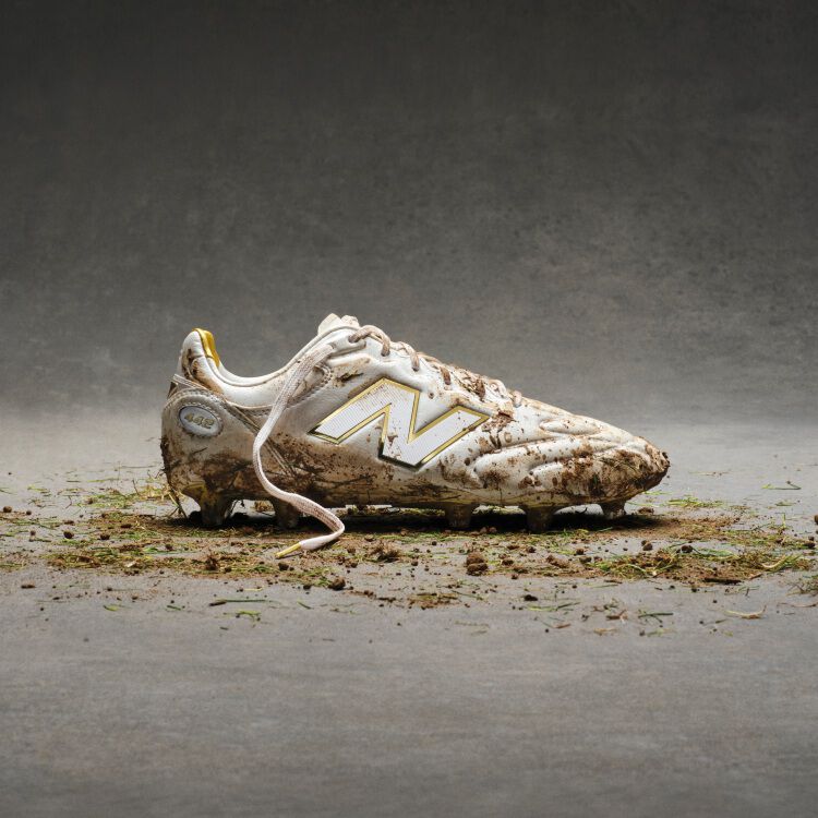 White and gold cleats covered in dirt and grass