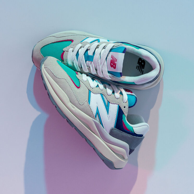 Top-down angle of a pair of grey 57/40 sneaker with multiple color details in a multi-colored studio environment.