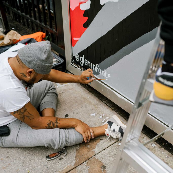 Glen Infante sitting painting the Lindor Mural