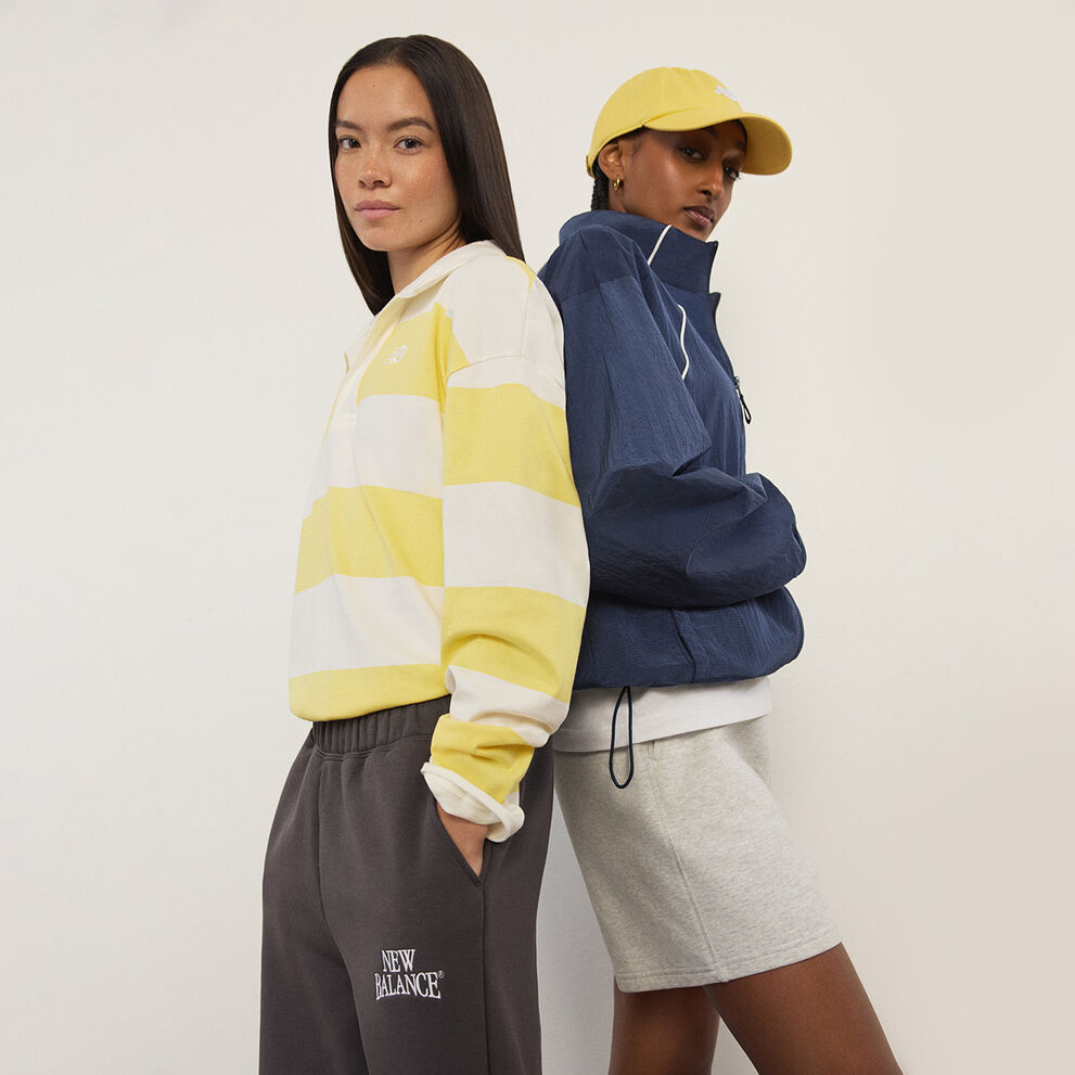 Two women standing in front of a white wall.