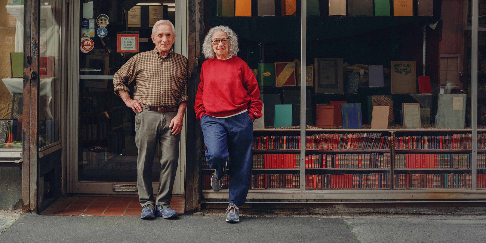 A man and woman standing on the street in front of a bookstore.