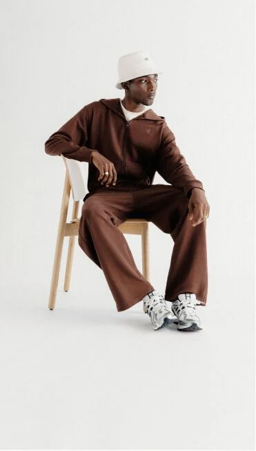 Man in a brown set sitting on a wooden chair. 