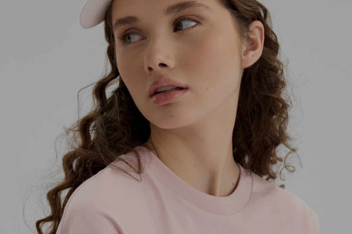 Close-up of a woman wearing a light pink shirt and hat.