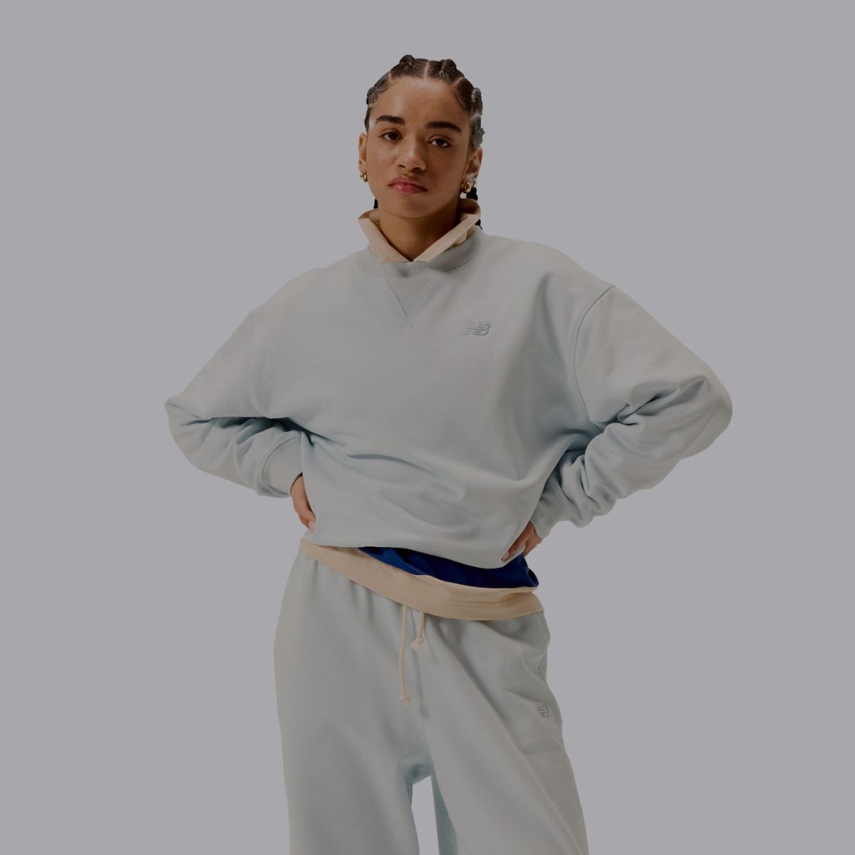 A woman wearing a grey matching set of New Balance clothes.