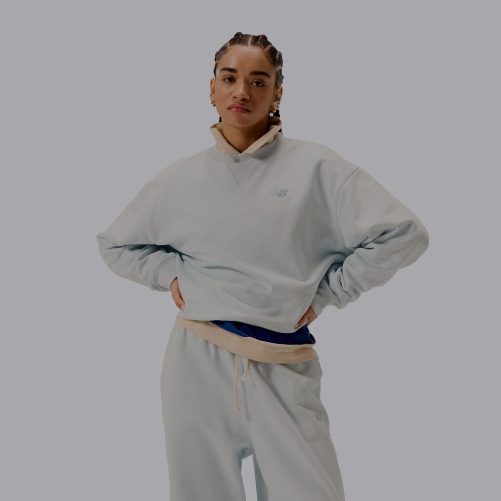 A woman wearing a grey matching set of New Balance clothes.