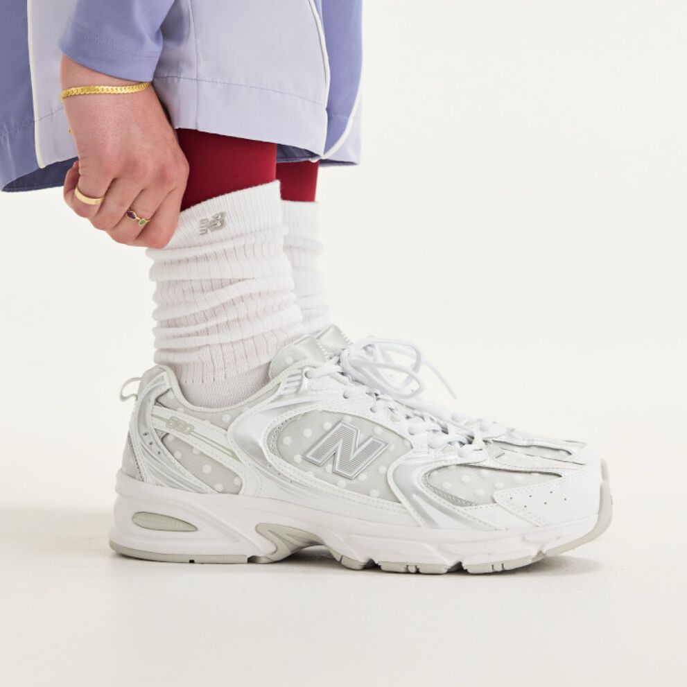 Side view of someone wearing white New Balance sneakers.