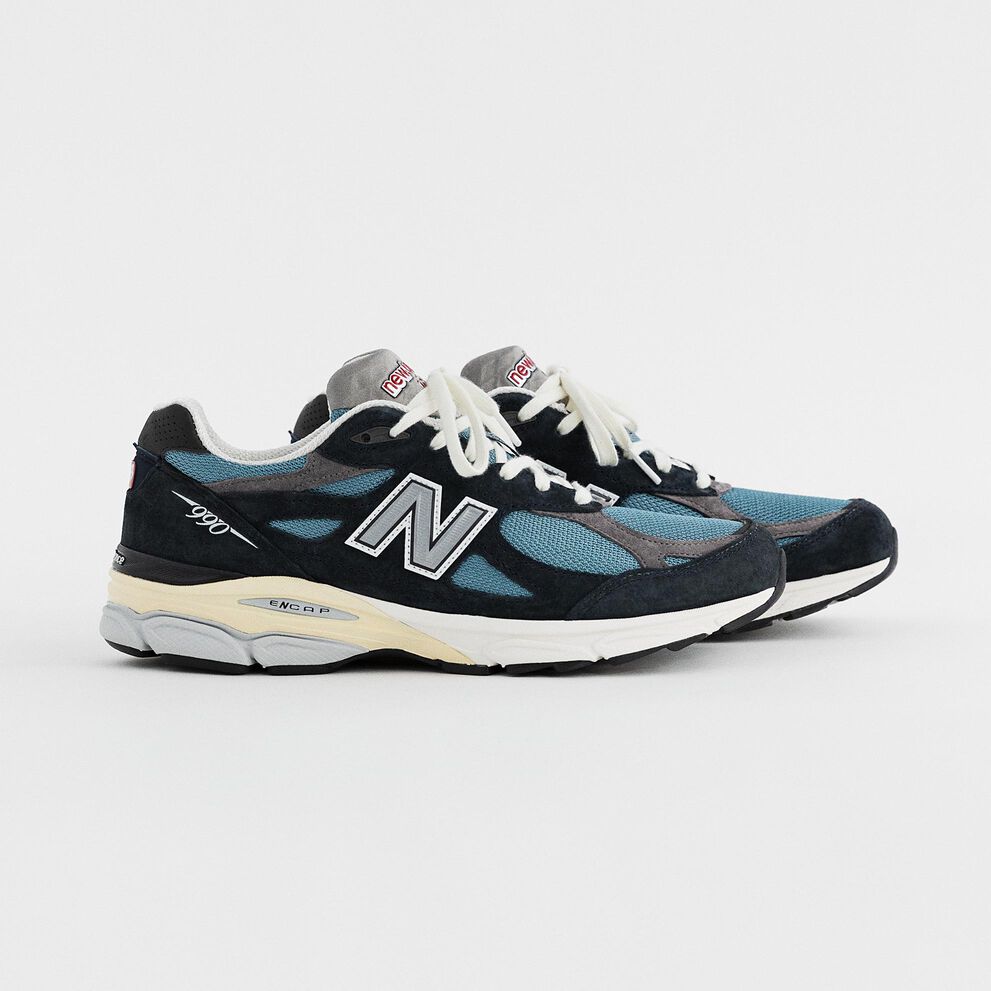 A pair of navy blue MADE in USA 990v3 on a grey studio backdrop.